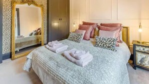 A bedroom with a large bed, a mirror, and a wardrobe. - Beautiful Cottage in Central Whitstable (Whitstable)