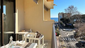 A balcony with a table set for two, overlooking a street with a hotel sign and a roundabout.