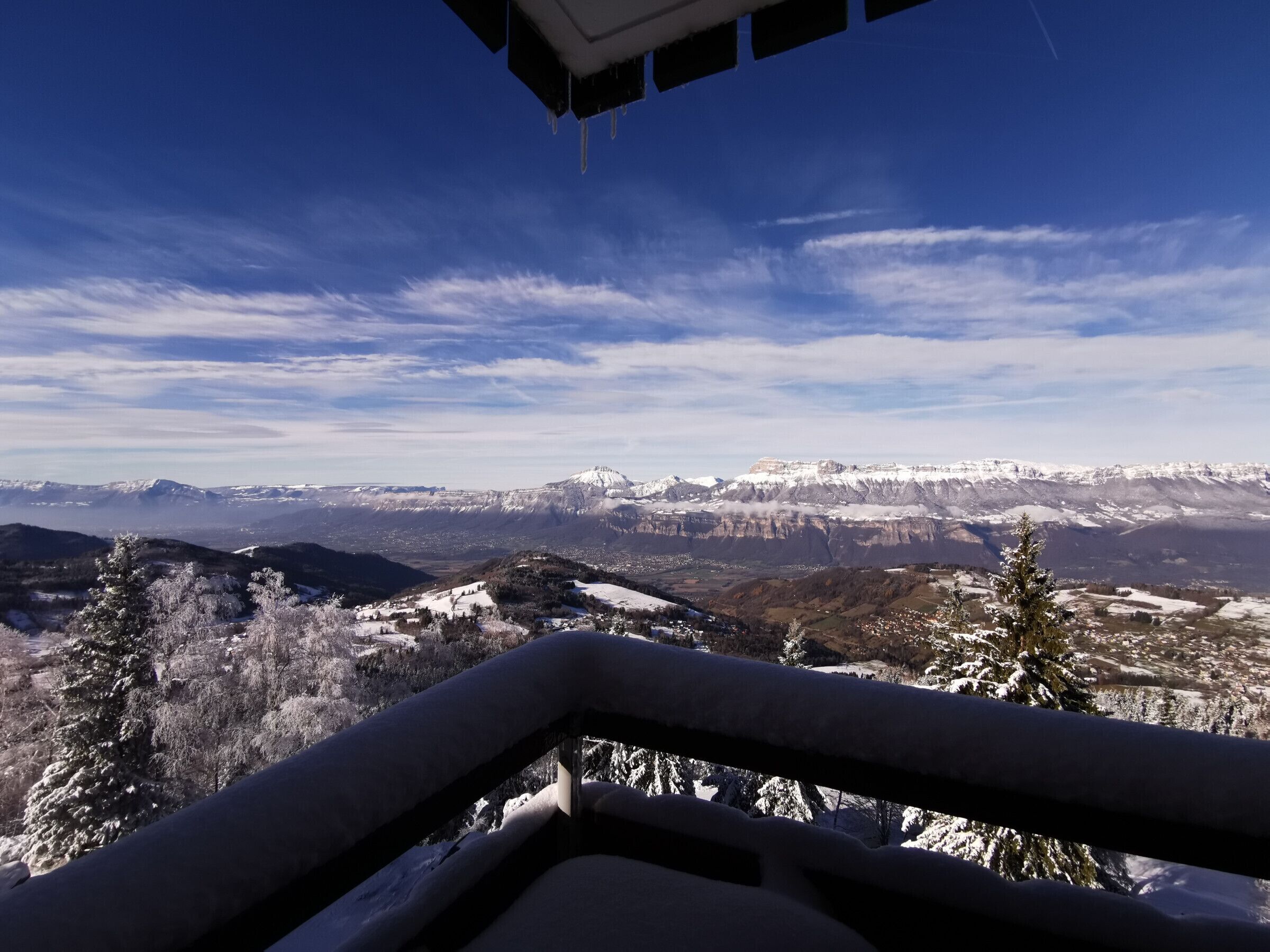 A panoramic view of a mountainous landscape with snow-covered peaks and a clear sky.