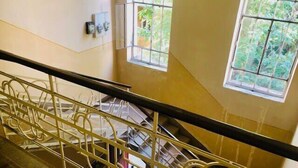 Una scala con ringhiere in metallo, un corrimano e vista su una stanza sottostante con una finestra e alcuni mobili.