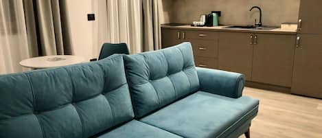 A modern living area with a sofa, a dining table, and a kitchen in the background.