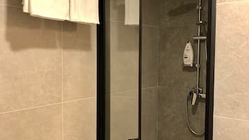 A modern bathroom with a glass-enclosed shower, a towel rack with two towels, and a bottle of Dove soap.