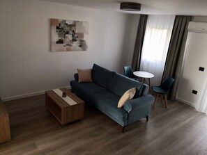 A modern living room with a sofa, a coffee table, a side table, and a small round table with chairs.