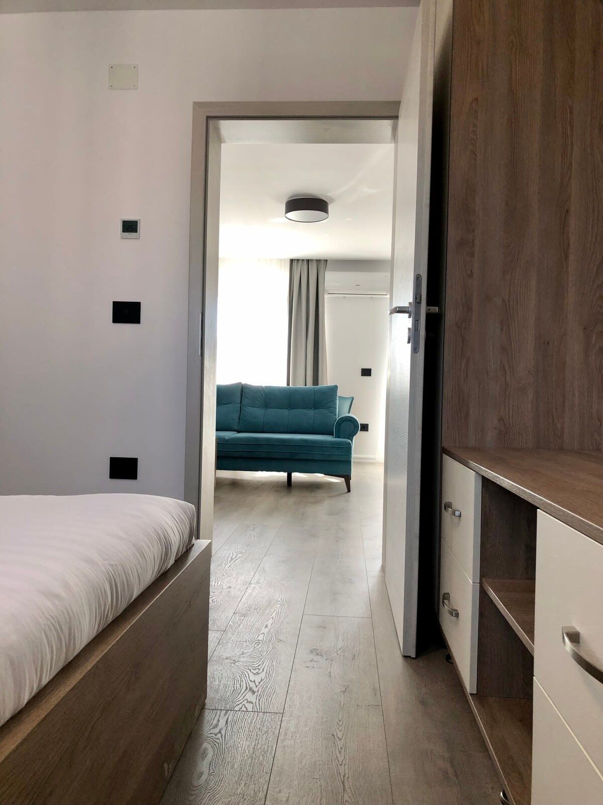 Een slaapkamer met een bed, een kledingkast en uitzicht op een andere kamer met een bank.