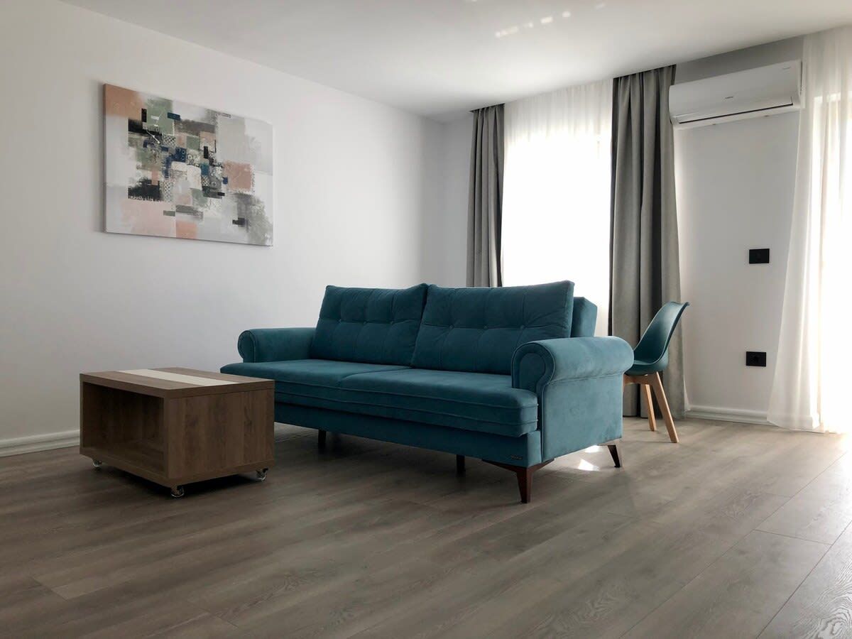 Een woonkamer met een smaragdgroene bank, een houten salontafel en een modern abstract schilderij aan de muur.
