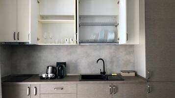 A modern kitchen with open cabinets, a black faucet, and a coffee maker.
