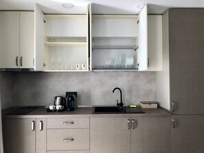 A modern kitchen with open cabinets, a black faucet, and a coffee maker.