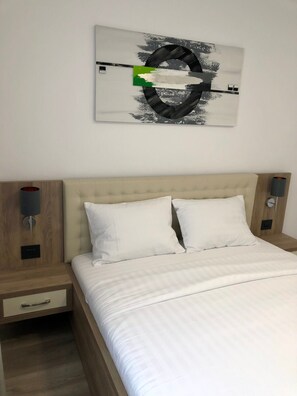 Une chambre à coucher comprenant un lit, deux tables de chevet et une œuvre d’art accrochée au mur.