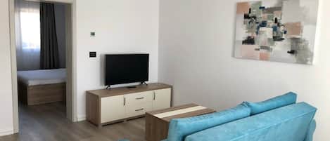 Un salón moderno con un sofá, un televisor en un mueble de madera y un cuadro en la pared.