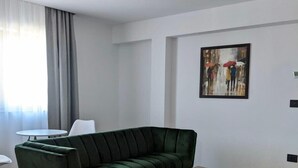 Een moderne woonkamer met een groene bank, een houten salontafel en een schilderij aan de muur.