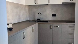 Een moderne keuken met grijze kastjes, een zwarte kraan en een structuurverzonken aanrechtblad.
