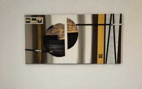 A bedroom with a bed, two white pillows, and a modern abstract painting above the bed.