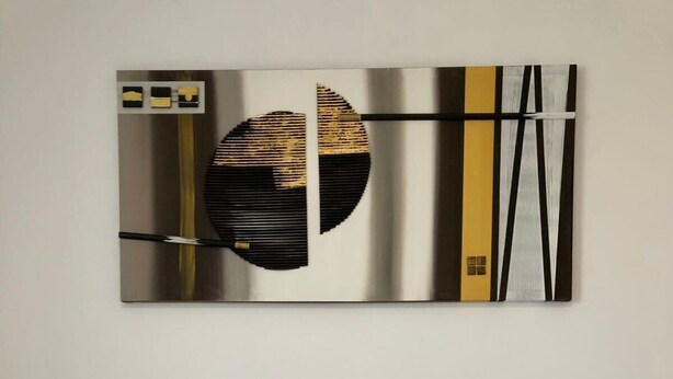 Een slaapkamer met een bed, twee witte kussens en een modern abstract schilderij erboven.