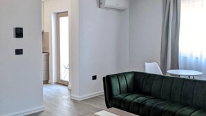 Een moderne woonkamer met een groene bank, een houten salontafel en een plafondlamp.