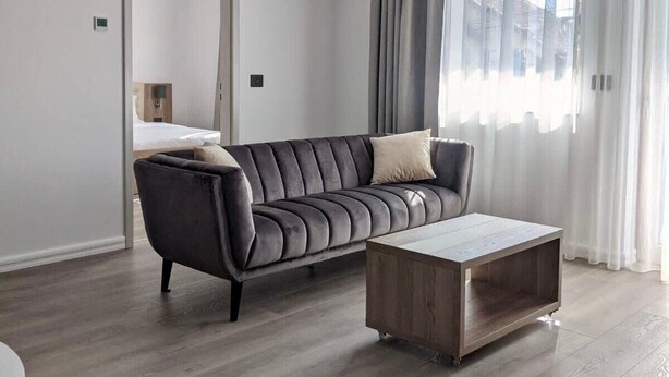 A modern living room with a dark grey sofa, a wooden coffee table, and light wooden flooring.