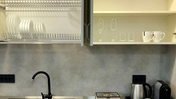 Eine moderne Küche mit einem schwarzen Spülbecken, einer Kaffeemaschine und einem Wasserkocher auf der Arbeitsfläche.