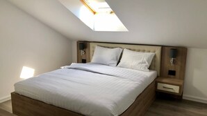 Ein modernes Schlafzimmer mit Oberlicht, einem Bettgestell aus Holz, weißer Bettwäsche und Nachttischen mit Lampen.