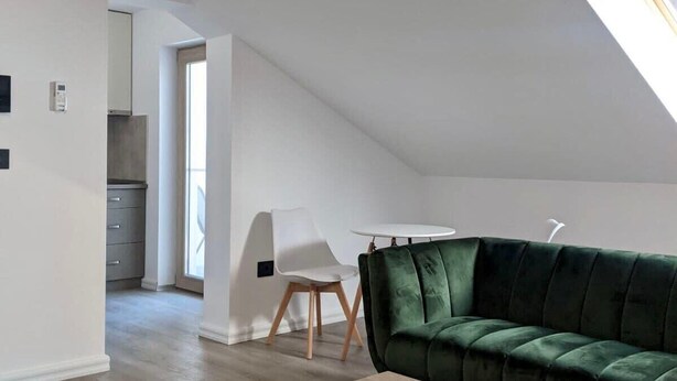 Um apartamento loft moderno com sofá de veludo verde, mesa de centro de madeira e cadeira branca.