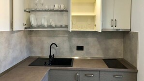 Cozinha compacta com duas pias, escorredor de louça e um armário.