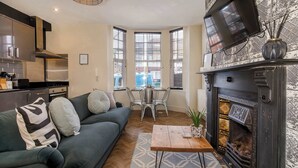 A modern living room with a sofa, coffee table, fireplace, and large windows.