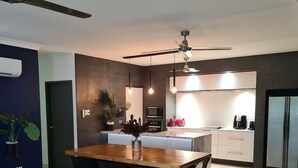 Eine moderne Küche mit Essbereich, ausgestattet mit einem Holztisch, schwarzen Stühlen und einem Deckenventilator.
