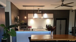Eine moderne Küche mit Kochinsel, schwarzen Stühlen und Deckenventilator.