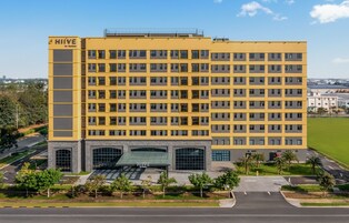 A multi-story hotel with a yellow facade, large windows, and a prominent entrance.