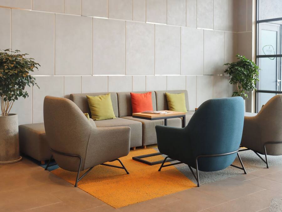 A modern lounge area with a sofa, two armchairs, a small table, and two potted plants.