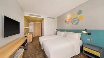 Una camera d'albergo moderna con un letto grande, una scrivania, una televisione e un bagno visibile attraverso una porta aperta.