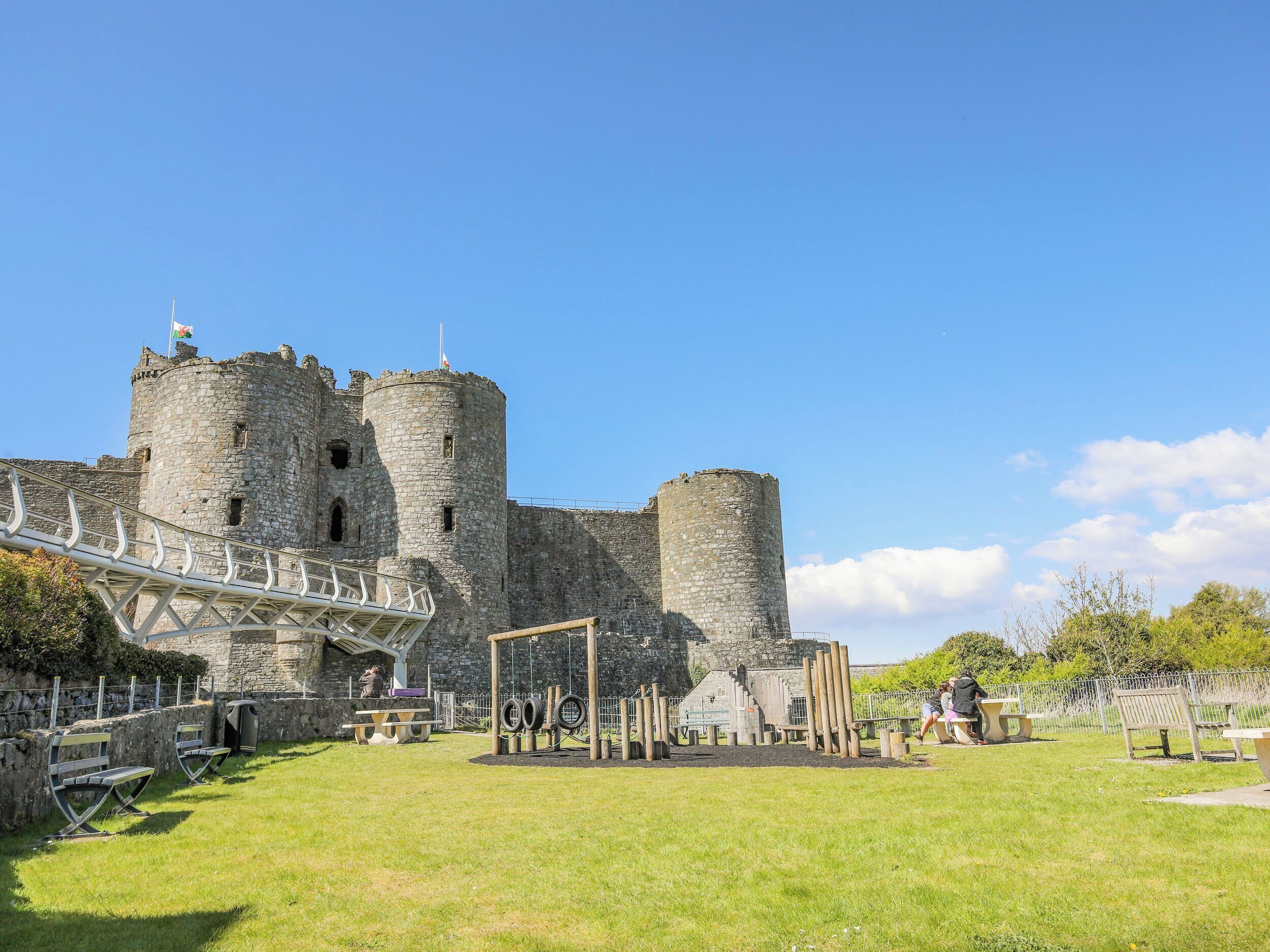 A historic castle with a stone tower and a paved walkway leading to the entrance.