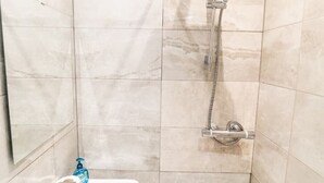 A bathroom with a shower, a toilet, and a bottle of hand soap on the floor. - [Covent Garden]Central London Apartment (London)