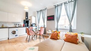 A modern hotel room with a bed, a dining area, a kitchen, and a TV displaying 'NETFLIX'. - [Covent Garden]Central London Apartment (London)