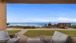 Une terrasse avec des sièges extérieurs, une vue sur l’océan et une clôture en bois.