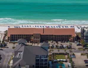 A hotel with a beach view, multiple parking lots, and a pool area.