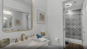 A bathroom with a white sink, gold faucets, a large mirror with a gold frame, a towel, and a toilet paper holder.
