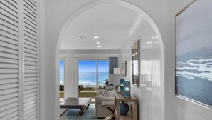 Un intérieur moderne avec vue sur l’océan, un canapé blanc et une petite table agrémentée d’objets décoratifs.