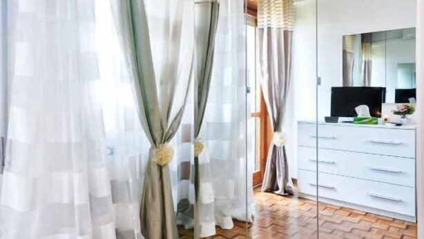 A room with a wooden herringbone floor, a large mirror, and a wardrobe with sliding doors. - Apt Venice City (Mestre)