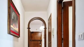 A hallway with a wooden parquet floor, a framed picture on the wall, and a door at the end. - Apt Venice City (Mestre)