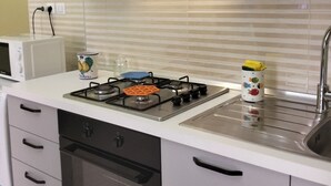 A kitchen with a gas stove, a microwave, a sink, and wooden cabinets. - Apartment a few minutes from the Sea (Letojanni)