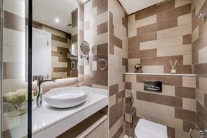 A modern bathroom with a large white sink, a mirror, a towel rack, and a shower area. - New modern studio on Palm Jumeirah (Dubai)