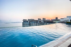 Ein moderner Infinity-Pool mit Blick auf die Skyline der Stadt bei Sonnenuntergang.