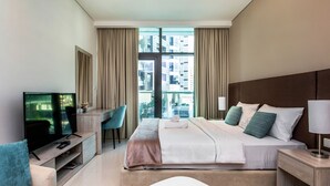 Ein modernes Hotelzimmer mit einem großen Bett, einem Schreibtisch mit Stuhl, einem Fernseher und Blick auf die Stadt durch große Fenster.