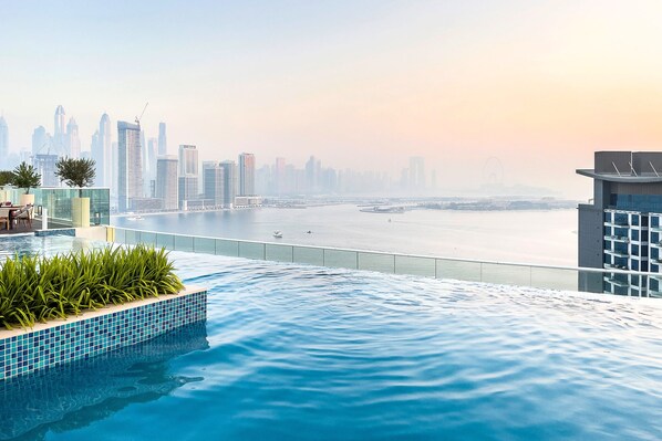 A rooftop infinity pool with a city skyline view, including a Ferris wheel. - New modern studio on Palm Jumeirah (Dubai)