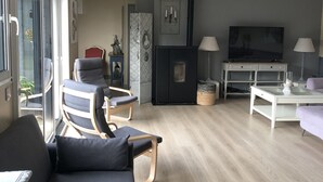 Un salon moderne avec un canapé, des fauteuils, un téléviseur et une cheminée.