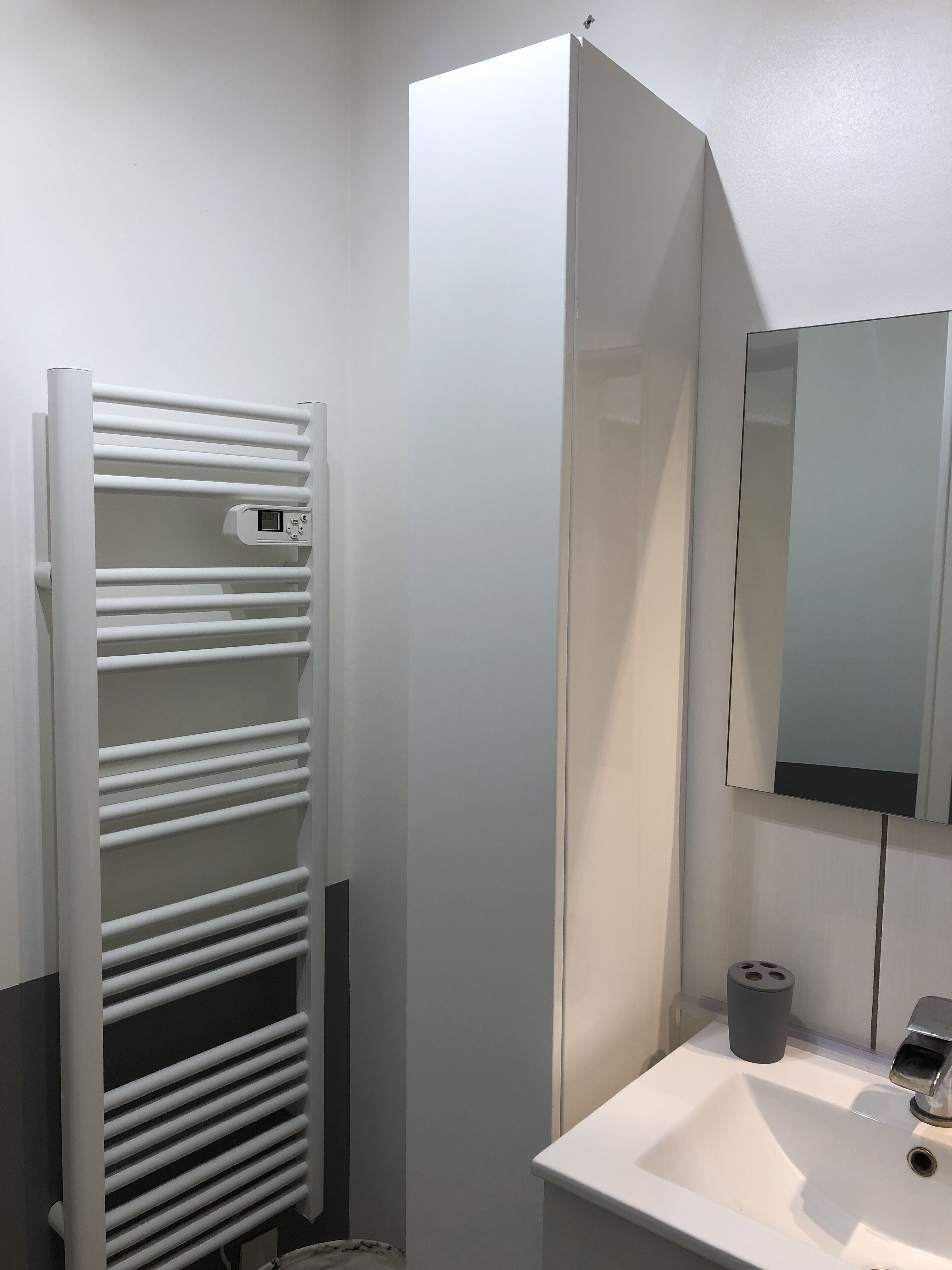 A bathroom with a white radiator, a sink, and a mirror.