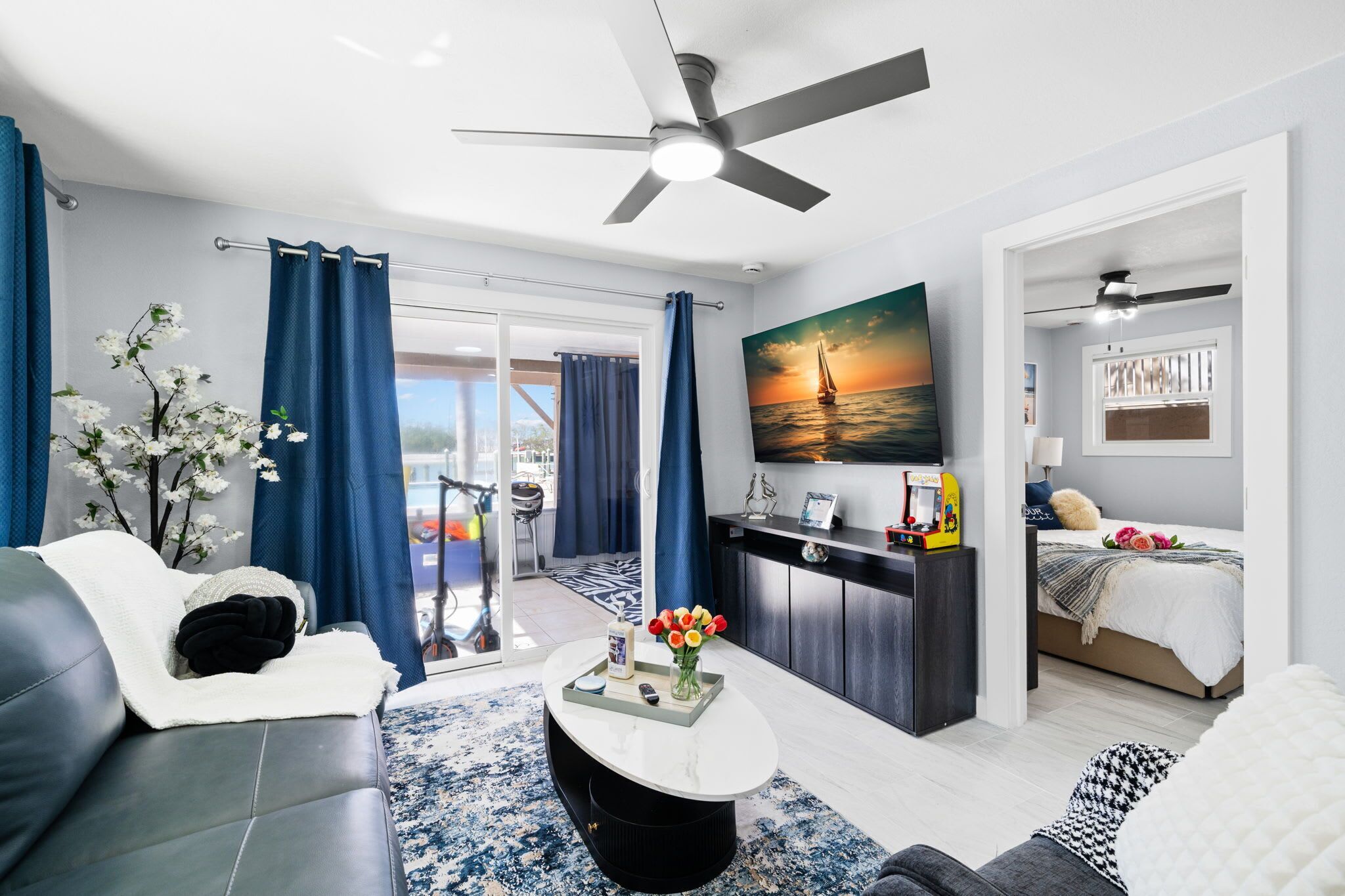 A modern living room with a sofa, coffee table, and a painting of a sunset.