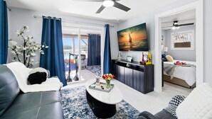 A modern living room with a sofa, coffee table, and a painting of a sunset.