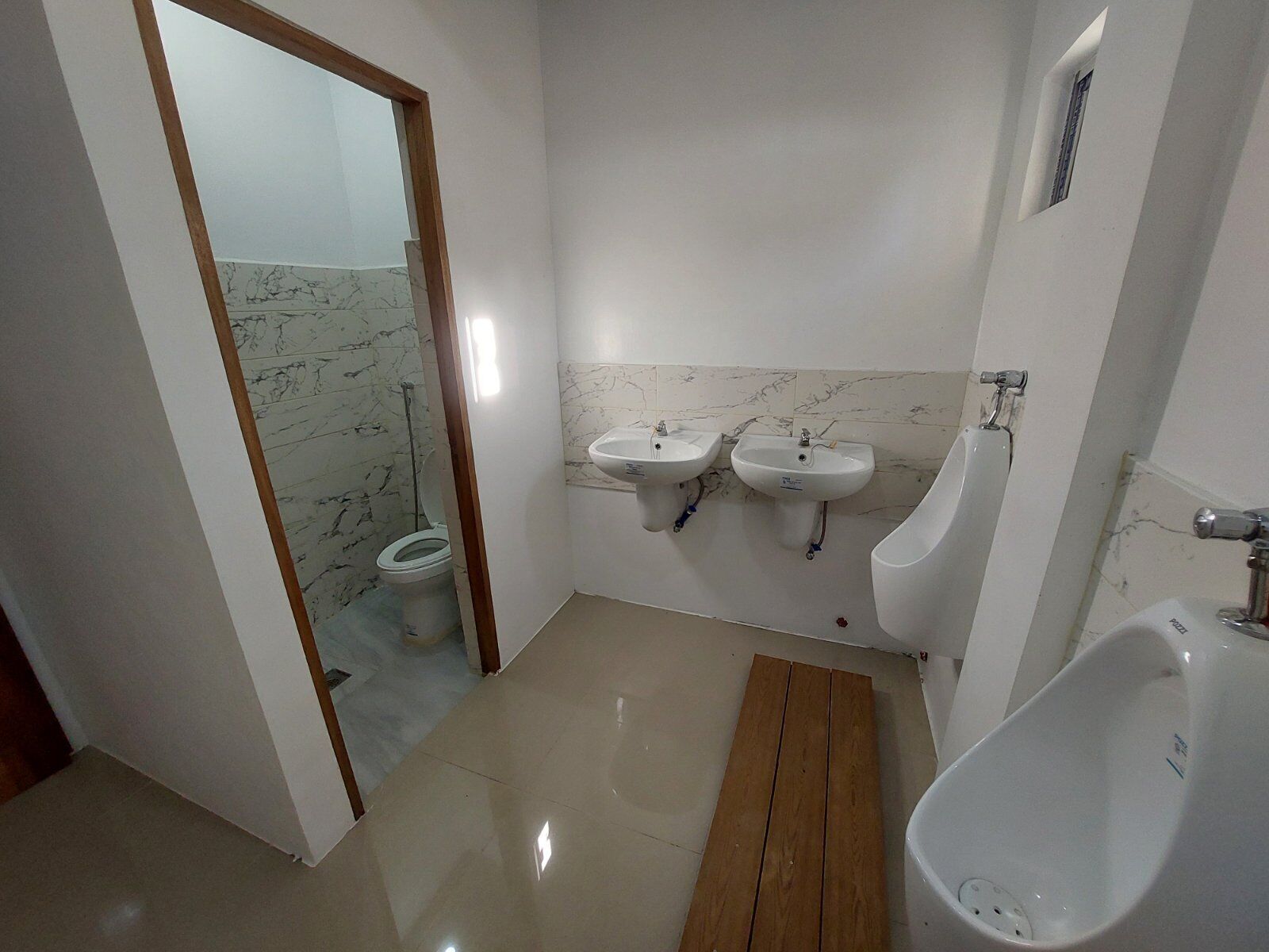A bathroom with a toilet, two sinks, and a urinal.