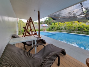 A poolside area with wicker furniture, a table, and a swing. - CMJ Private Resort  (Indang)