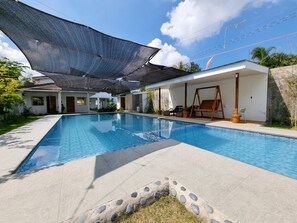 A swimming pool with a shaded area, a swing chair, and a covered seating area. - CMJ Private Resort  (Indang)